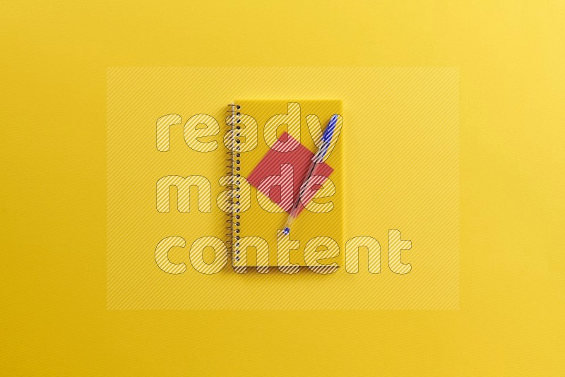 A yellow notebook with school supplies on yellow background (Back to school)
