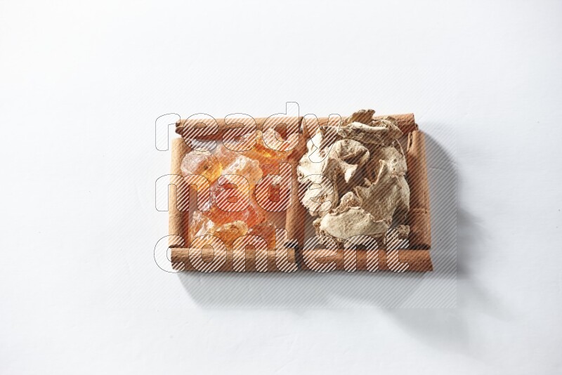 مربعان من أعواد القرفة ممتلئان بالزنجبيل المجفف والصمغ العربي علي خلفية بيضاء