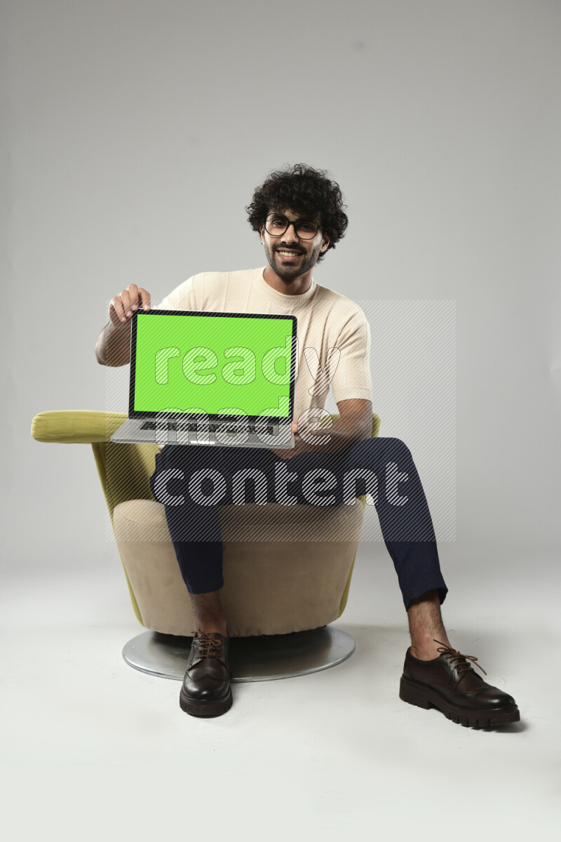A man wearing casual sitting on a chair showing a laptop screen on white background