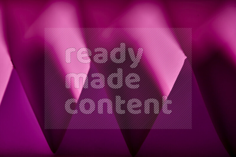 صورة مجردة مقربة تظهر طيات ورقية هندسية حادة بتدرجات اللون الارجواني