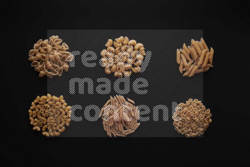 Different pasta types in bunches on black background