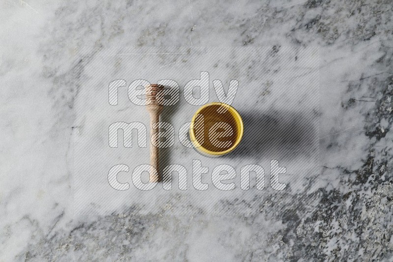 Multicolored Pottery Cup with wooden honey handle on the side on grey marble flooring, Top view
