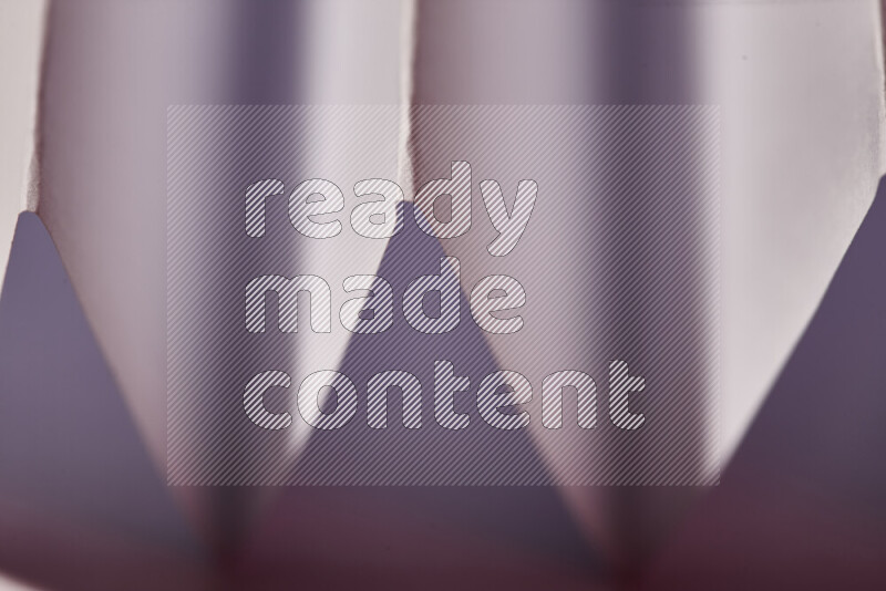 صورة مجردة مقربة تظهر طيات ورقية هندسية حادة بتدرجات اللون الأبيض و الوردي