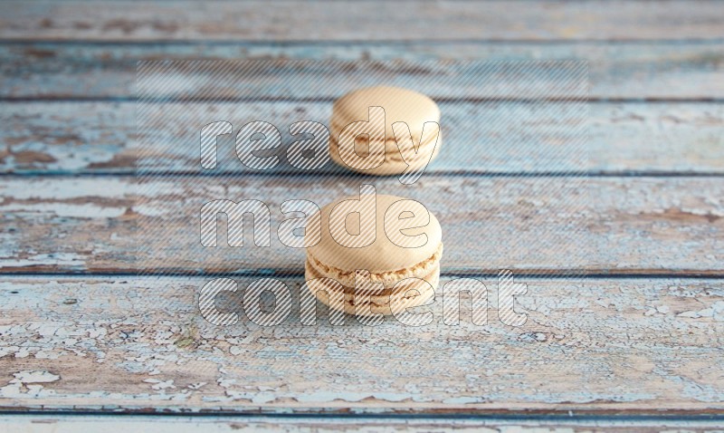45º Shot of two White Caramel fleur de sel macarons on a light blue wooden background