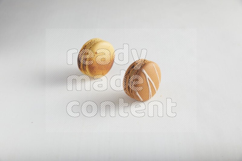 45º Shot of of two assorted Brown Irish Cream, and Yellow Crème Brulée macarons on white background