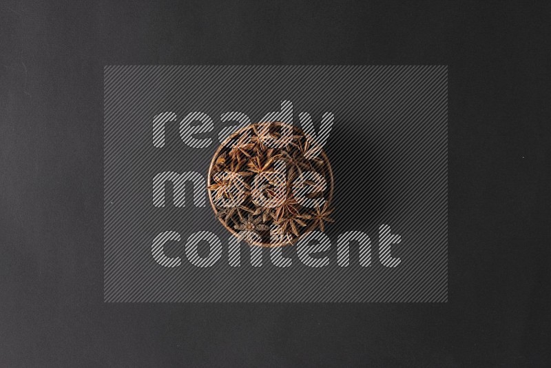 Star Anise in a wooden bowl on black flooring