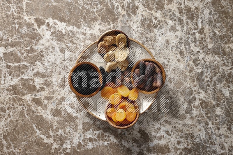 Dried fruits in pottery plates and wooden bowls in a light setup