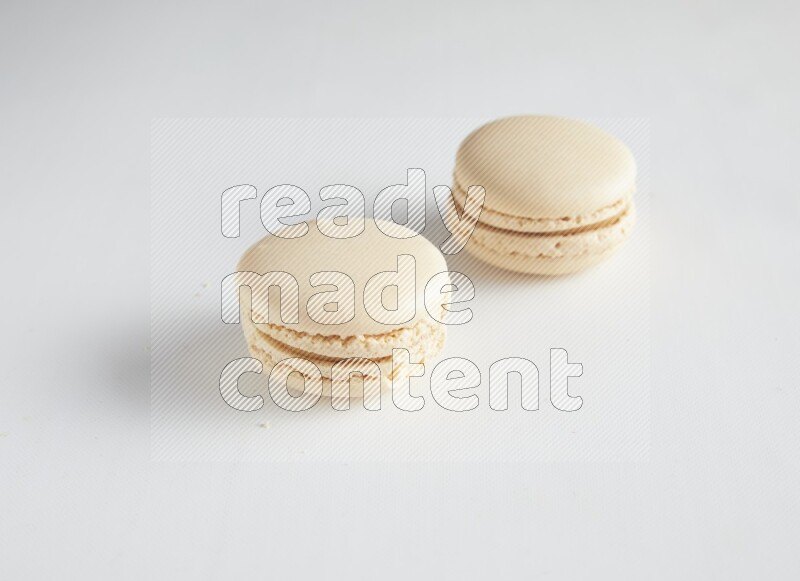 45º Shot of two White Caramel fleur de sel macarons on white background