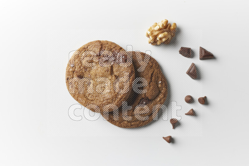 Chocolate chips cookies with chocolate and walnuts beside it on a white background