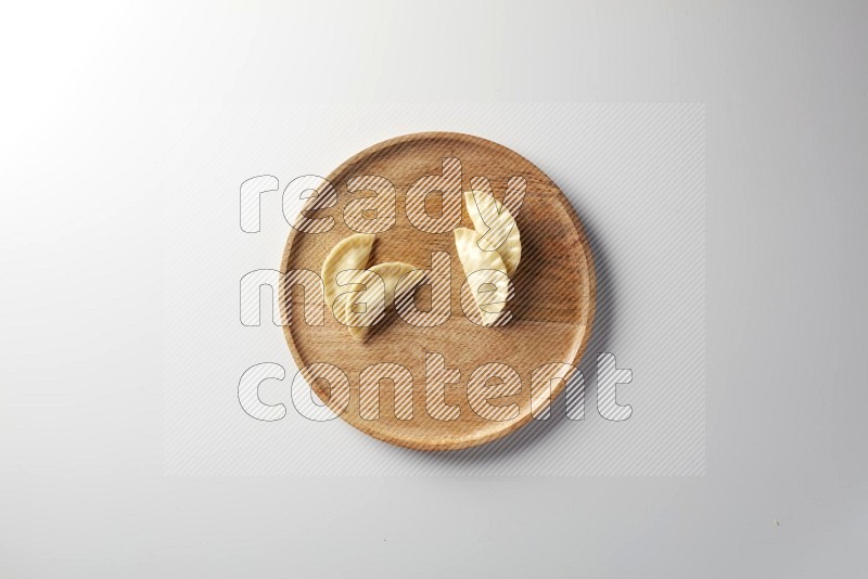 Four Sambosas on a wooden round plate on a white background