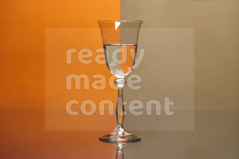 The image features a clear glassware filled with water, set against orange and beige background
