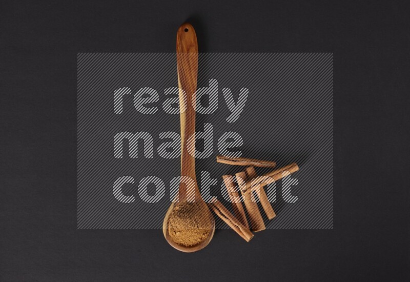 Cinnamon powder in a wooden ladle spoon beside it cinnamon sticks on the flooring on black background in different angles