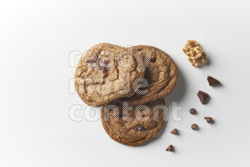 Chocolate chips cookies with chocolate and walnuts beside it on a white background