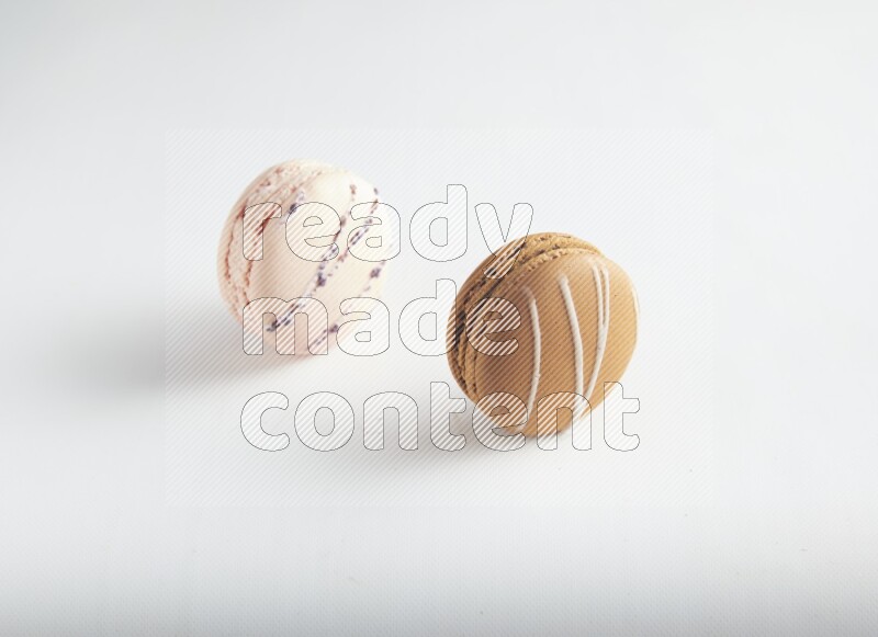 45º Shot of of two assorted Brown Irish Cream, and pink orange blossom macarons on white background