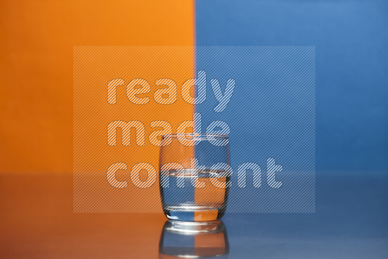 The image features a clear glassware filled with water, set against orange and blue background