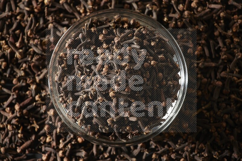 A glass bowl full of cloves on a black flooring