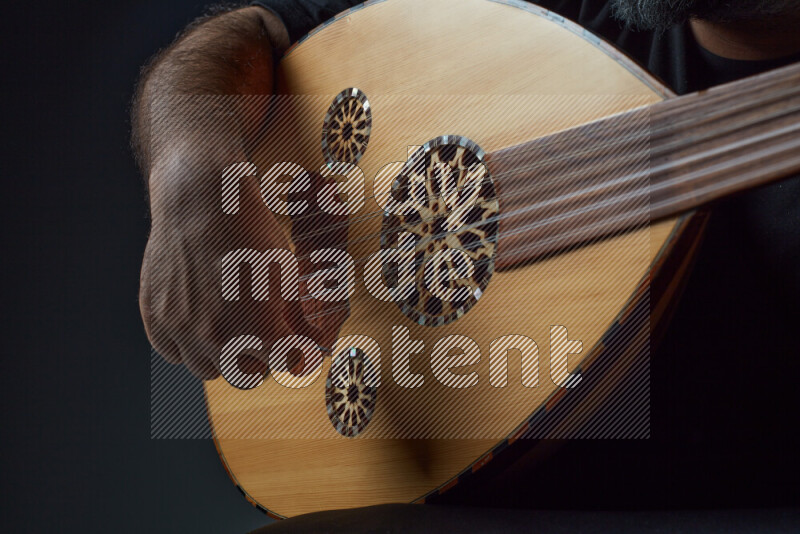 يد رجل تعزف على عود خشبي بني