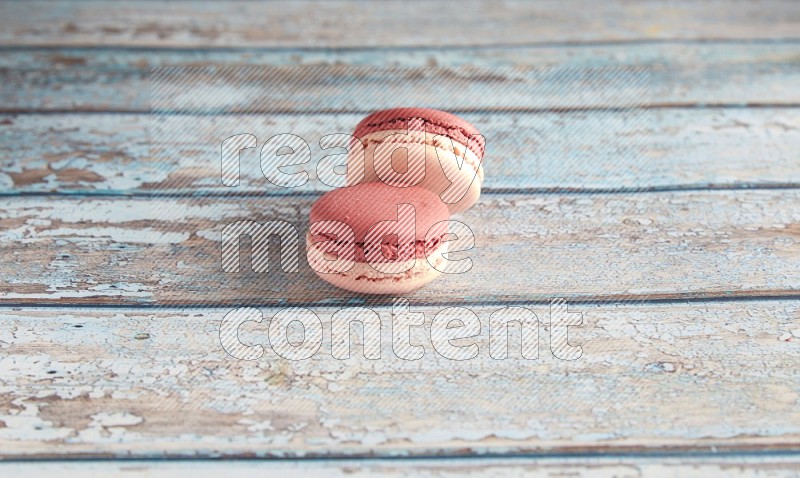 45º Shot of two Pink Litchi Raspberry macarons on light blue wooden background