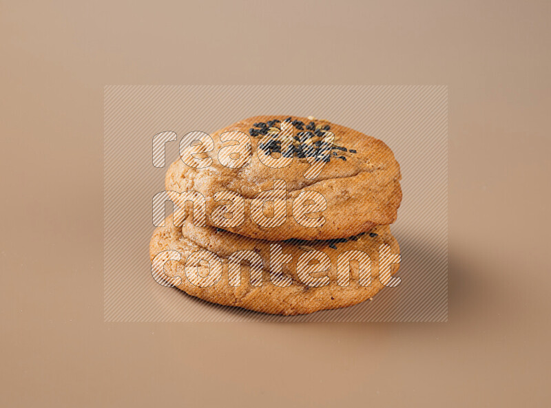 Two chocolate chip cookies on a brown background
