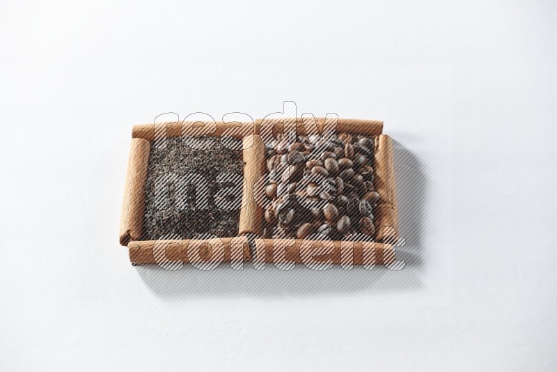 مربعان من أعواد القرفة ممتلئان بحبوب القهوة والشاي الأسود علي خلفية بيضاء