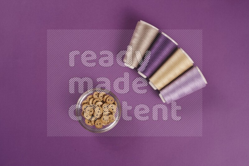 A beige collection of sewing and tailoring tools arranged on a purple background