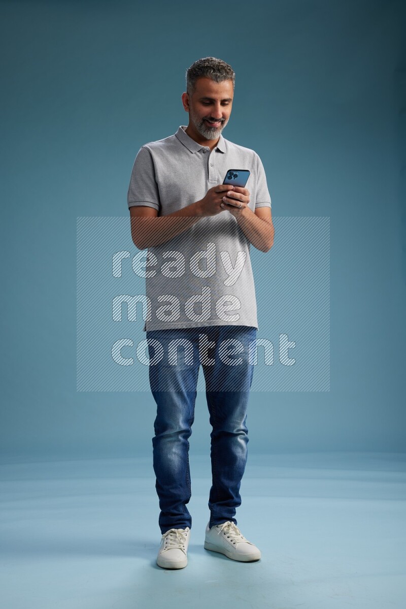Man Standing texting on phone on blue background