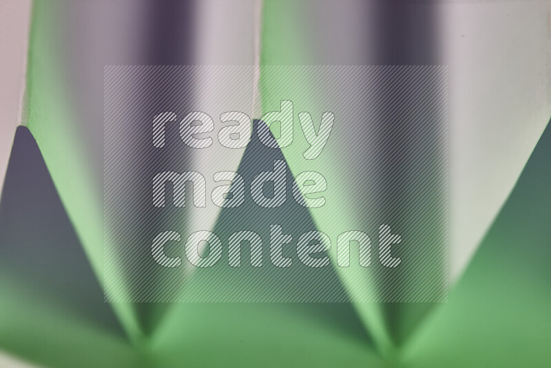 A close-up abstract image showing sharp geometric paper folds in white and green gradients