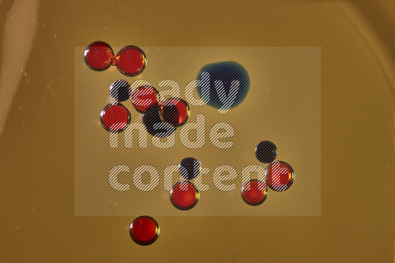 Close-ups of abstract red and blue watercolor drops on oil Surface on yellow background