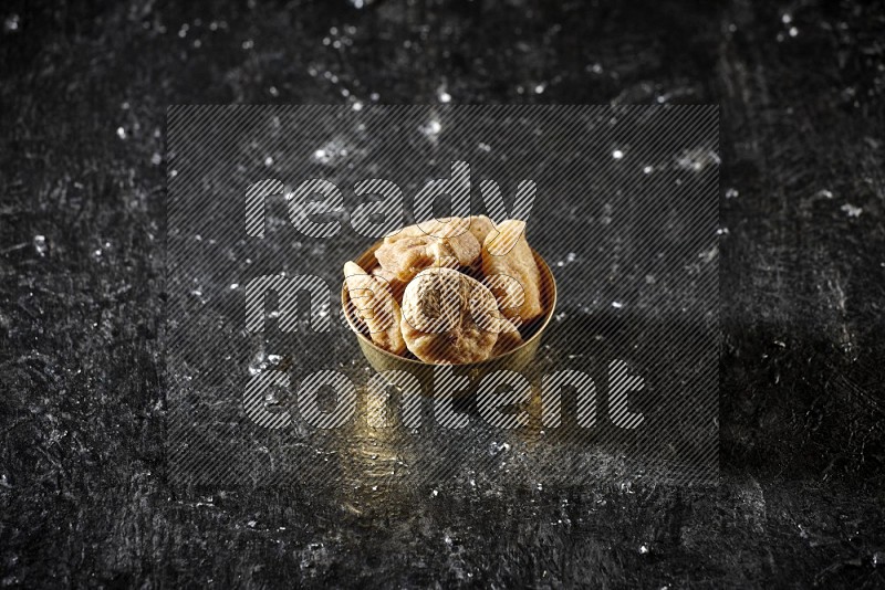 Dried fruits in a metal bowl in a dark setup