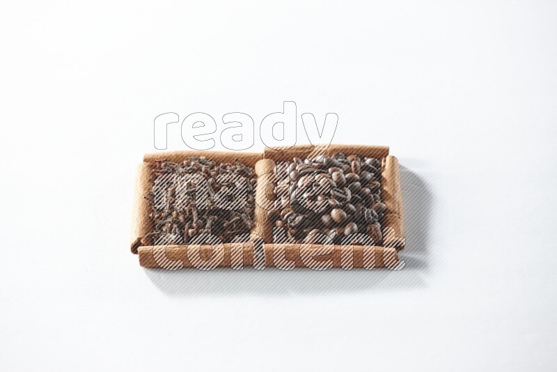 مربعان من أعواد القرفة ممتلئان بحبوب القهوة والقرنفل علي خلفية بيضاء