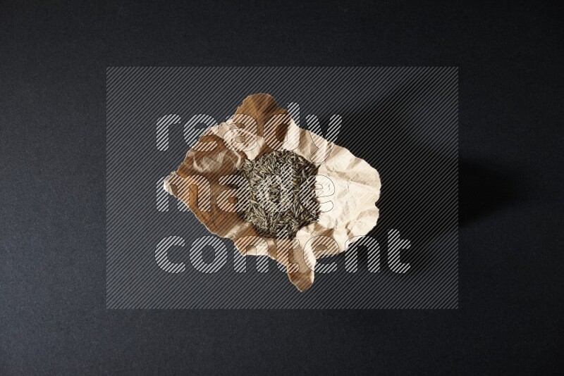 حبوب الكمون في قطعة من الورق على خلفية سوداء