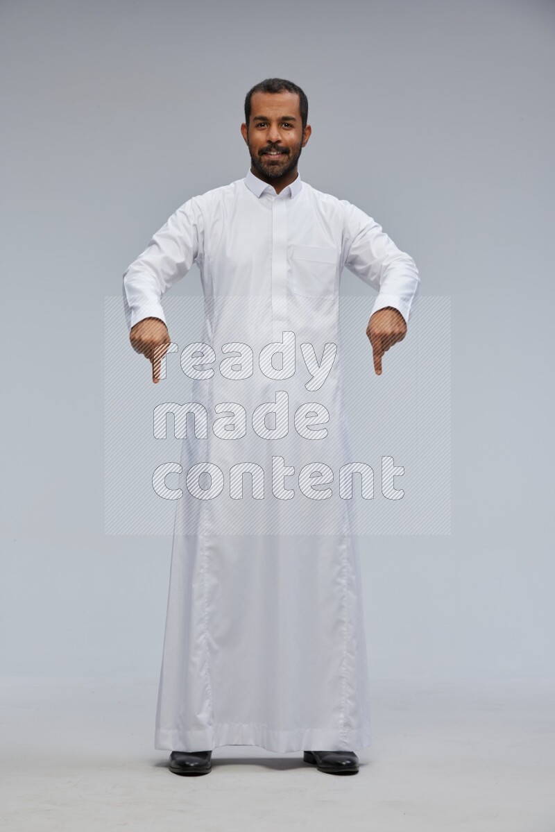 Saudi man Wearing Thob standing interacting with the camera on Gray background