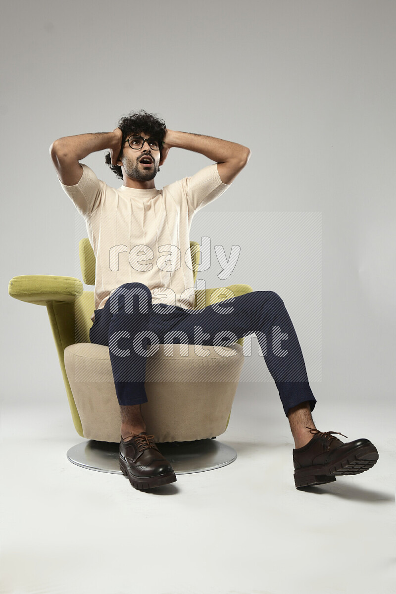رجل يرتدي ملابس كاجوال يجلس علي كرسي و يقوم بإشارات باليد علي خلفية بيضاء