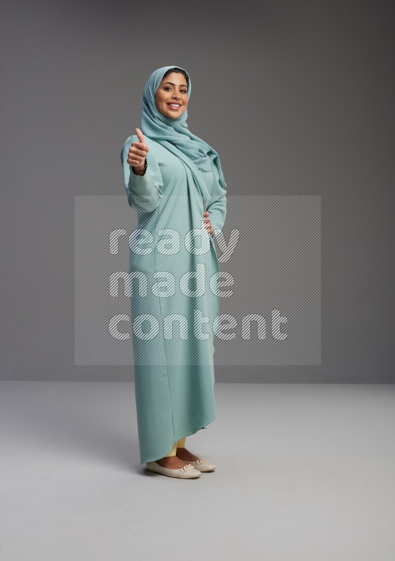 Saudi Woman wearing Abaya standing interacting with the camera on Gray background