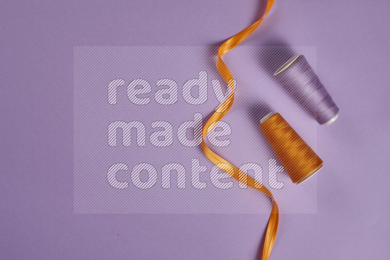 An orange collection of sewing and tailoring tools arranged on a purple background