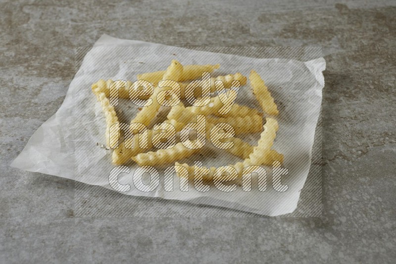crinkle fries on parchment paper on grey textured counter top