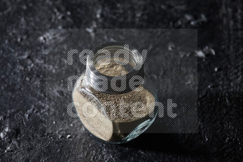 وعاء زجاجي ممتلئ بالفلفل الأبيض على أرضية سوداء