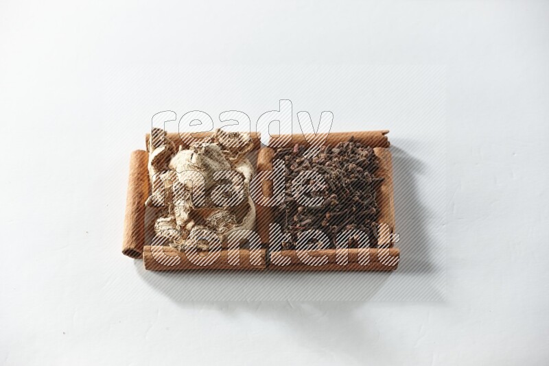 مربعان من أعواد القرفة ممتلئان بالقرنفل والزنجبيل المجفف علي خلفية بيضاء