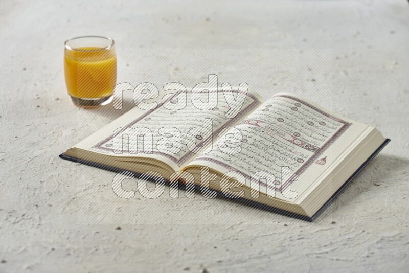 Quran with dates, prayer beads and different drinks all placed on textured white background