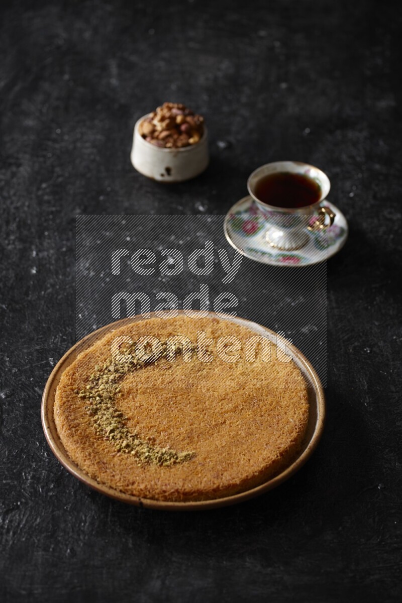 Konafa with nuts and tea in a dark setup