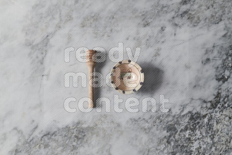 Decorative pottery bowl with wooden honey dipper on the side on grey marble background