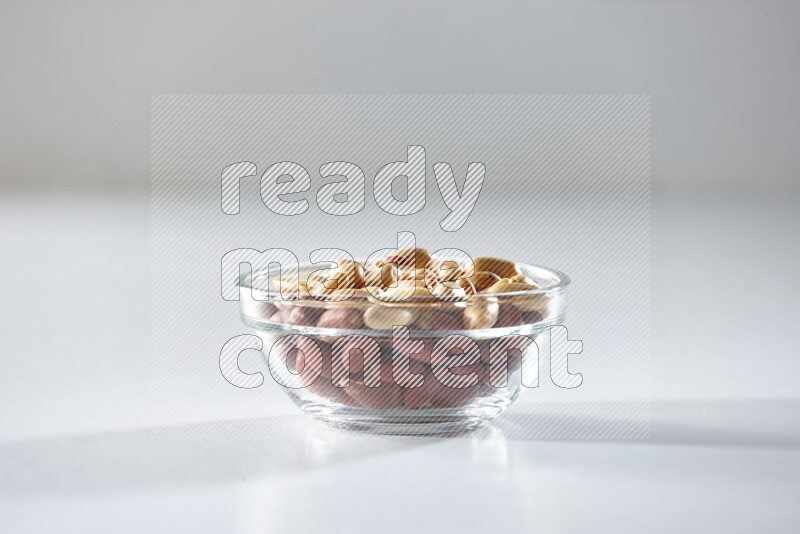 A glass bowl full of peeled peanuts on a white background in different angles