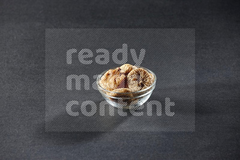 A glass bowl full of dried figs on a black background in different angles
