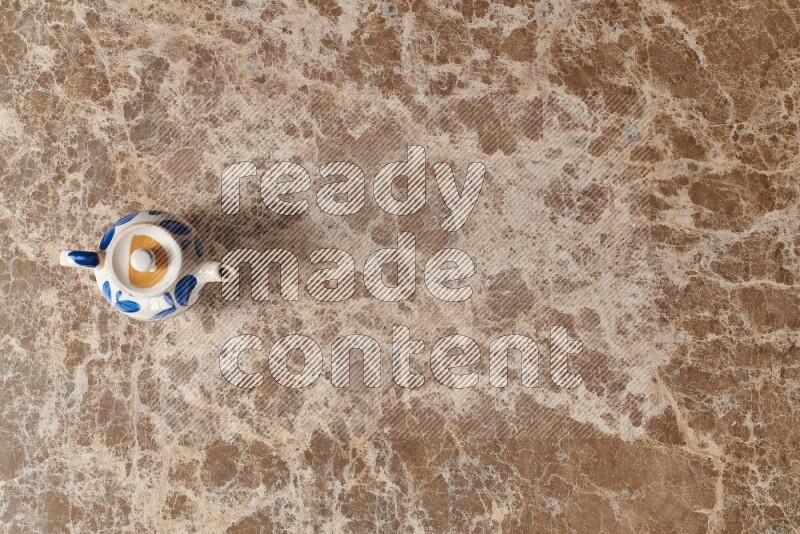 A pottery teapot on beige marble background