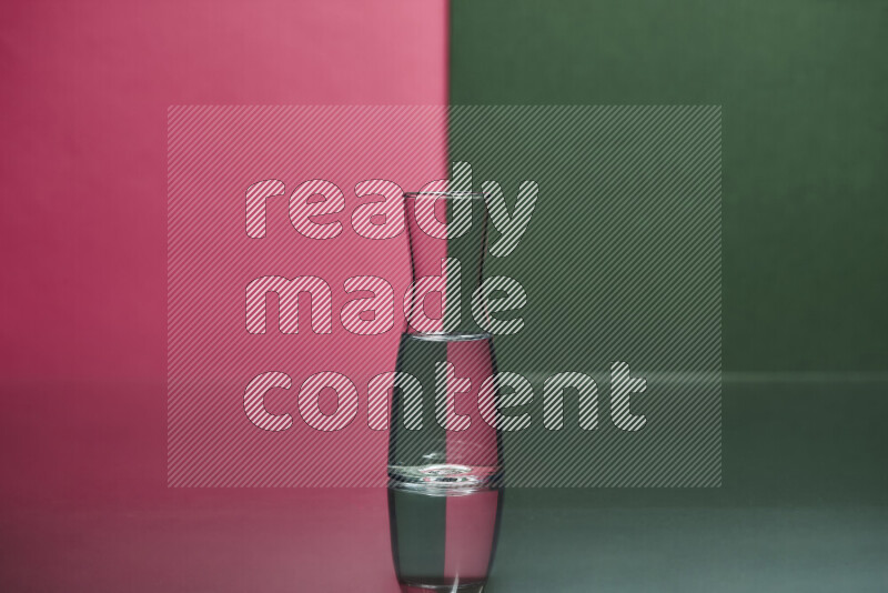 The image features a clear glassware filled with water, set against pink and dark green background