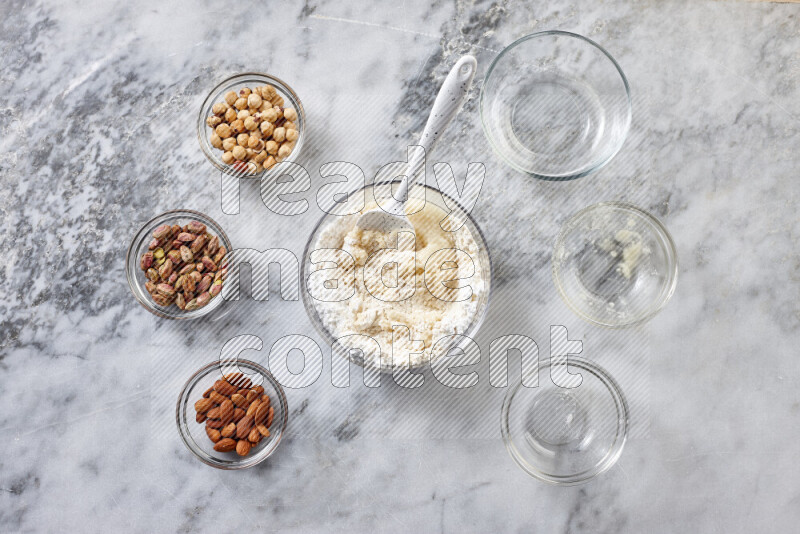 Ghoriba step by step with its ingredient, flour, powdered sugar, ghee and nuts on grey marble background