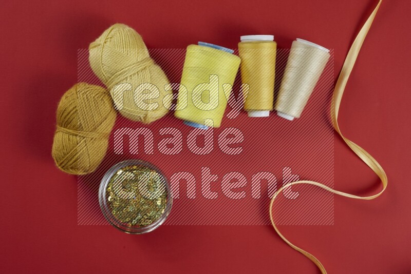 A yellow collection of sewing and tailoring tools arranged on a red background