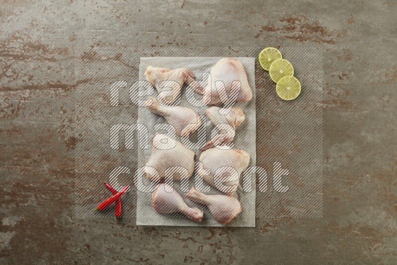 Mixed fresh chicken pieces on a parchment paper direct on a textured rustic background