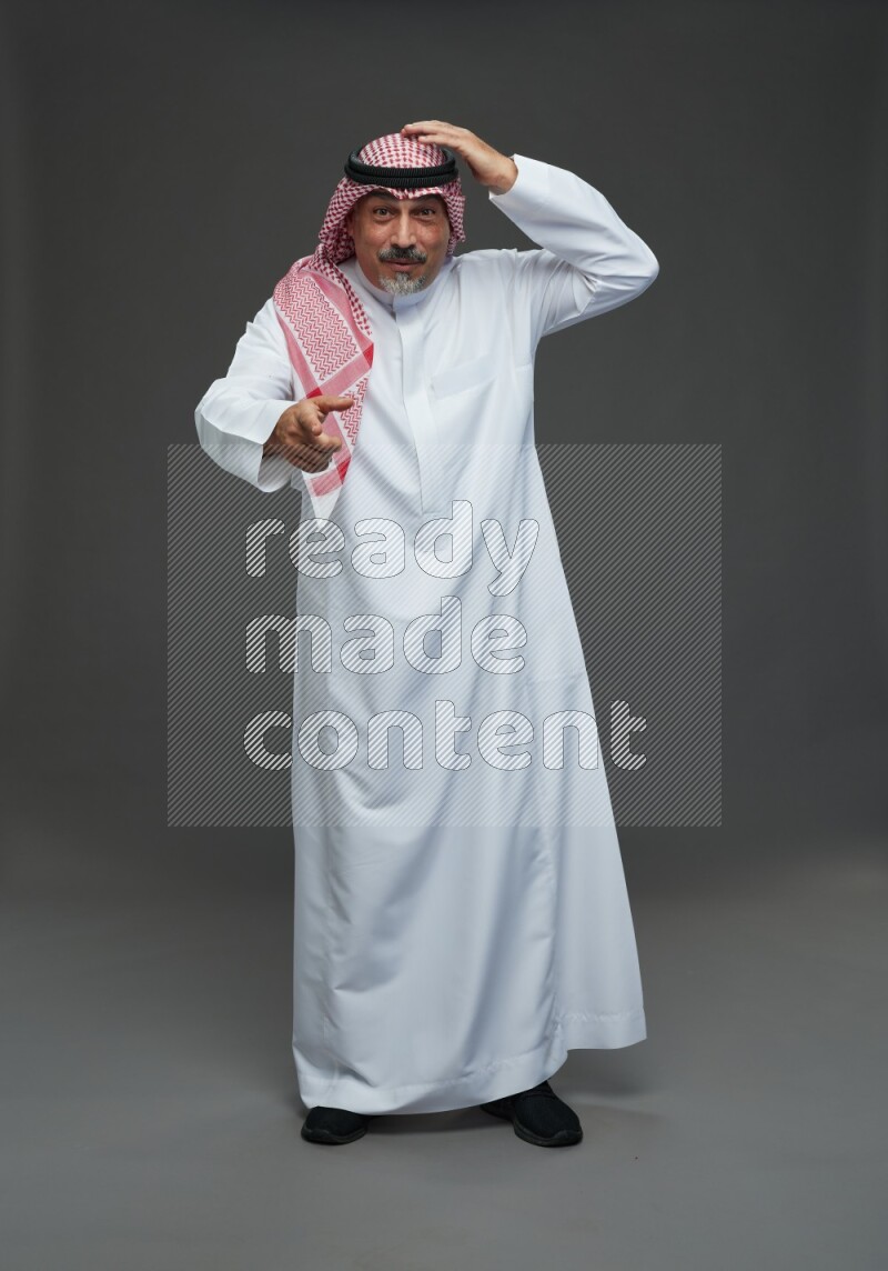 Saudi man with shomag Standing Interacting with the camera on gray background