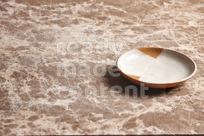 A multicolored pottery plate on beige marble background